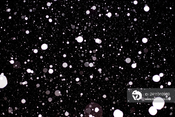 Large flakes of snow against the black sky, swirling in the light of lantern. - Image