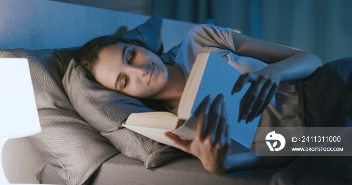 Woman lying in bed and reading a book