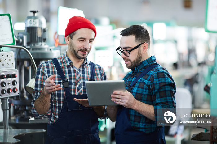 Waist up  portrait of two factory workers using digital tablet in workshop