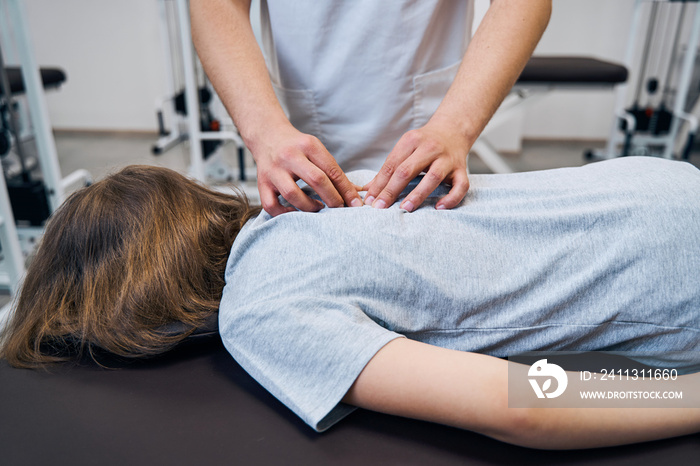 Physiotherapist checks girl with spine deformity at session in rehabilitation room. Manual therapist