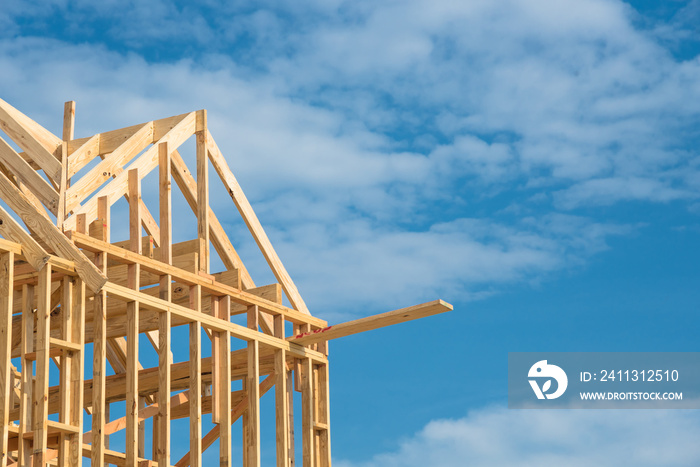 Close-up new stick built home under construction under blue sky in Humble, Texas, US. Framing structure/wood frame of wooden houses/home. House construction and real estate concept background.