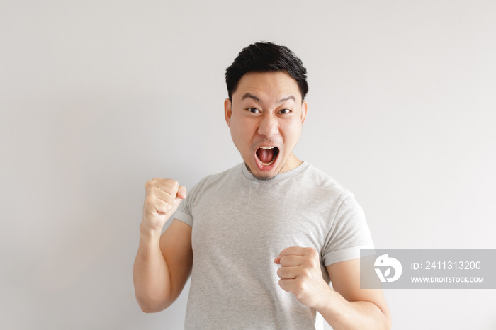 Asian man feels excited. The man wears grey t-shirt on grey background.