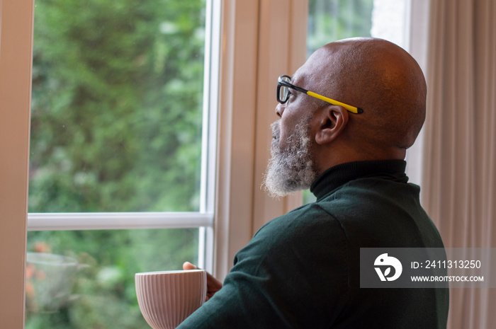 Mature man looking out living room window