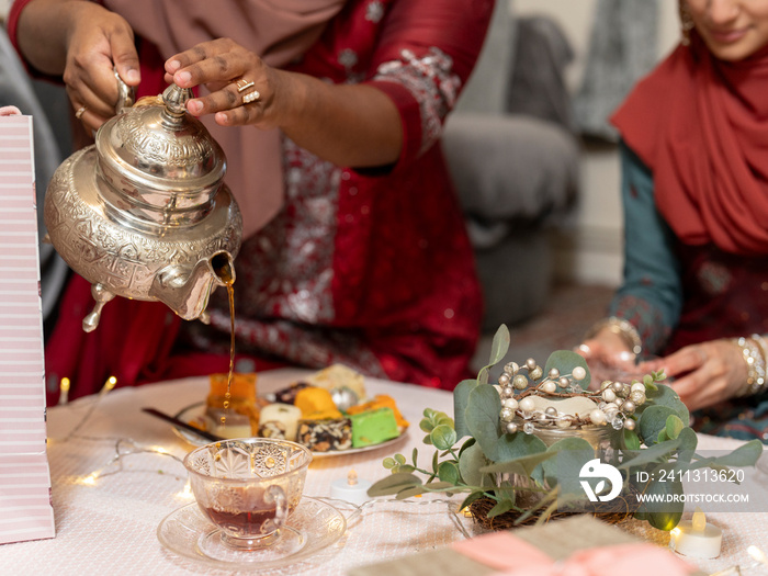 Woman pouring tea during Ramadan celebration at home