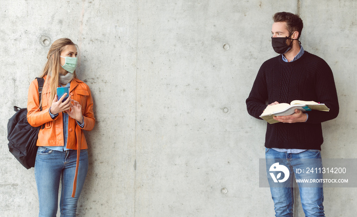 Two students standing in social distance wearing face mask