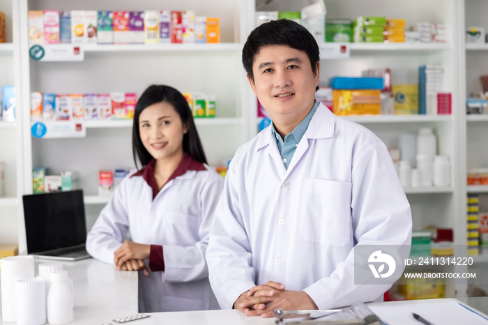 Two Male and female pharmacists smiling happy to Service in drugstore Thailand health care and business concept