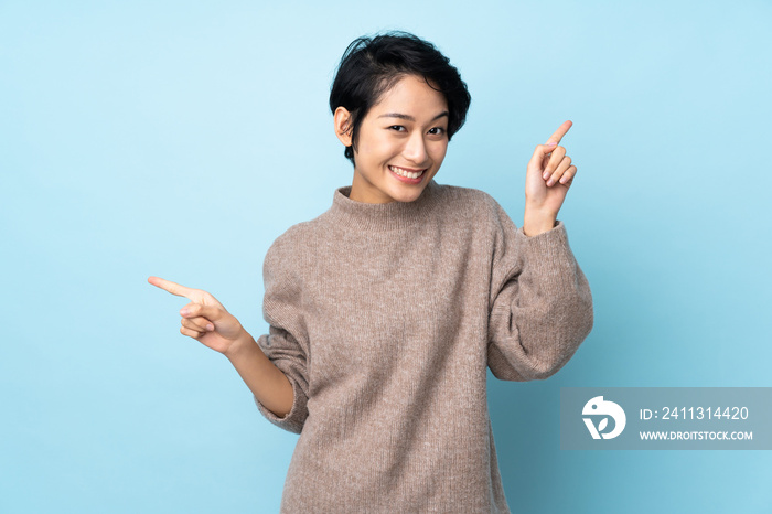 Young Vietnamese woman with short hair over isolated background pointing finger to the laterals and happy