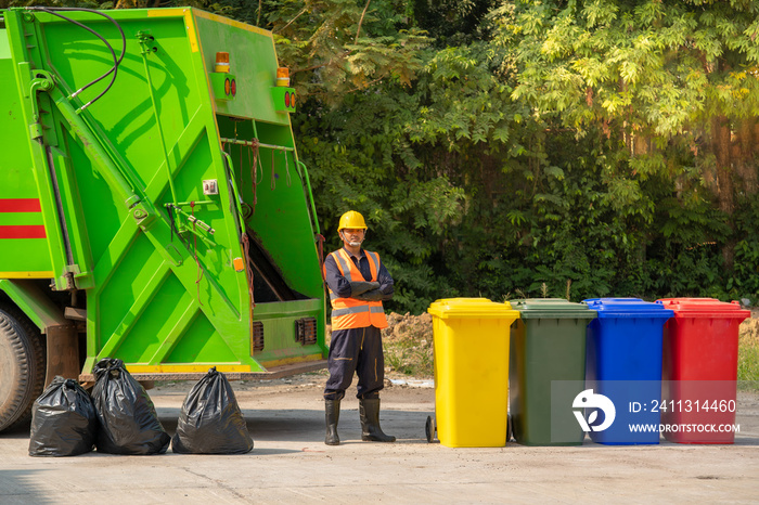 Garbage removal worker in protective clothing working for a public utility emptying trash container.