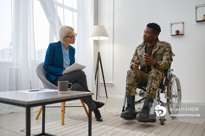 Paraplegic soldier in wheelchair talking with therapist