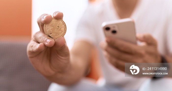 Young hispanic man holding litecoin crypto currency using smartphone at home