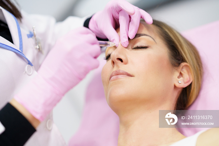 Doctor performing rhinoplasty by injection of hyaluronic acid in the nose of his patient.