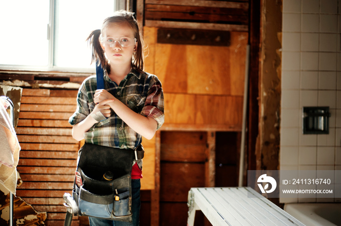 Portrait of girl holding hammer while standing at home