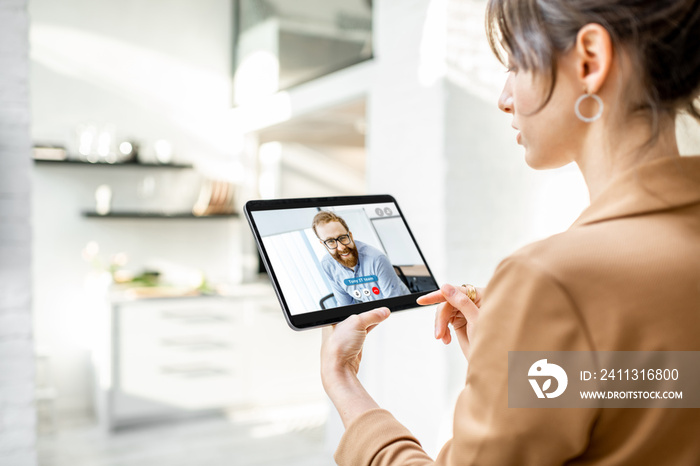 Business woman having a video call with coworker using a digital tablet, while working from home