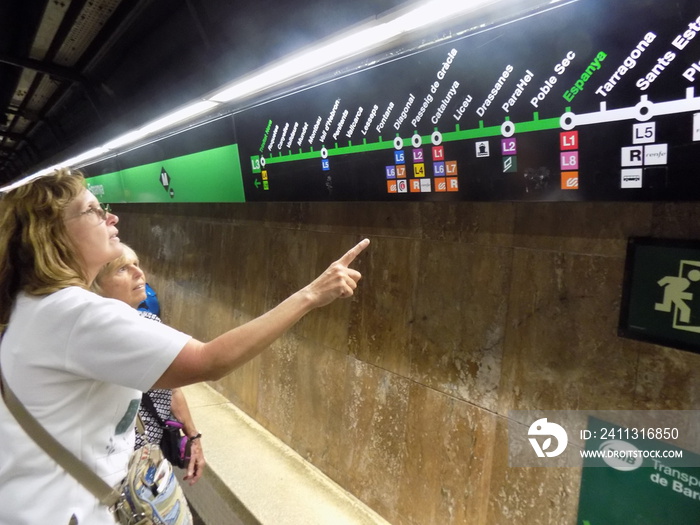 Two Women Exploring Barcelona, Spain, By Subway as they Look at the Map to Find their Next Metro  Stop