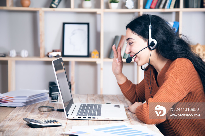 woman in headphones speaking looking at laptop