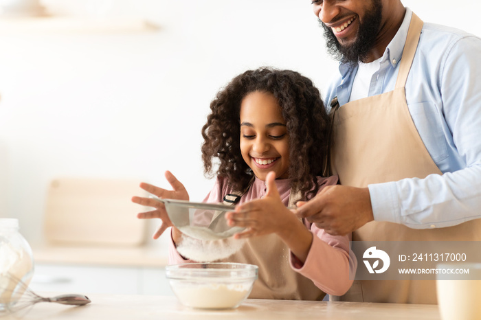 Cheerful black man and his daughter preparing dough