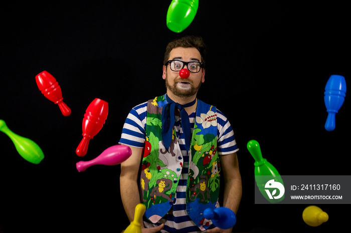 Clown Juggler. Clown juggling colorful Skittles on a black background