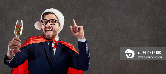 Businessman in a Santa Claus costume, a superhero with a glass of champagne congratulates Merry Christmas on a background for the text.