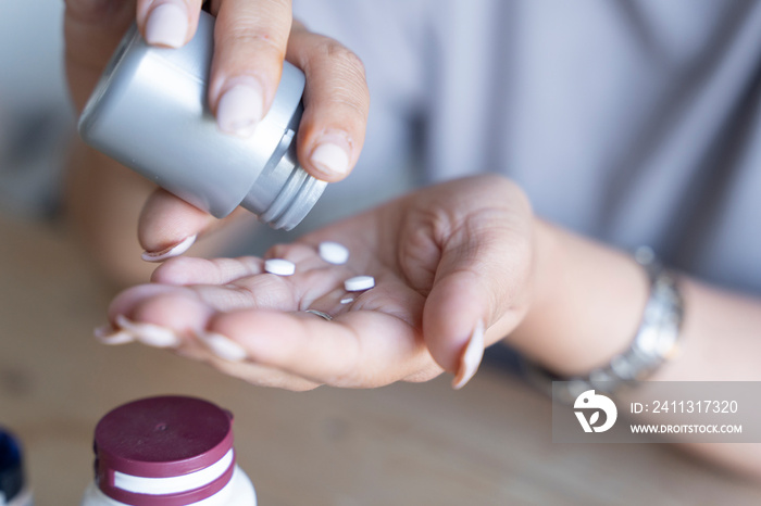 Woman taking vitamins from bottle