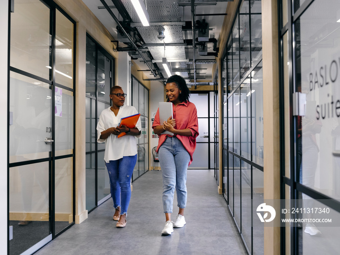 Two women walking in office hallway