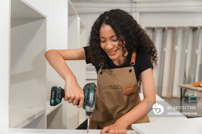 Carpenter African American woman use electric screwdriver at wood factory