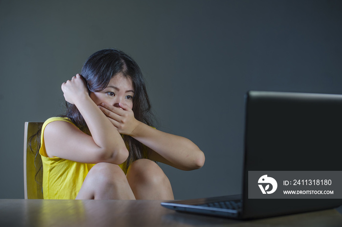 young pretty shocked and surprised Asian Korean woman looking stressed at laptop computer feeling amazed and scared in cyber bullying concept