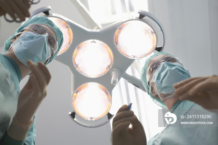 Low angle view of two surgeons preparing to operate in operating theatre