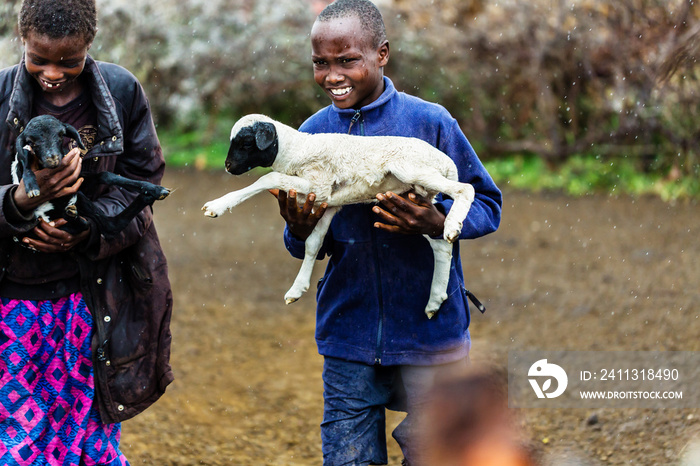 Massai children carrying goats in the rain