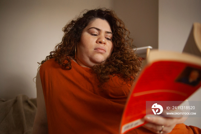 Plus-sized Sri Lankan woman with vitiligo reading in her bedroom