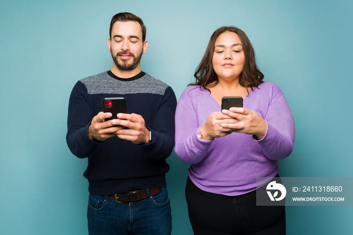 Attractive young man and woman texting on their smartphones