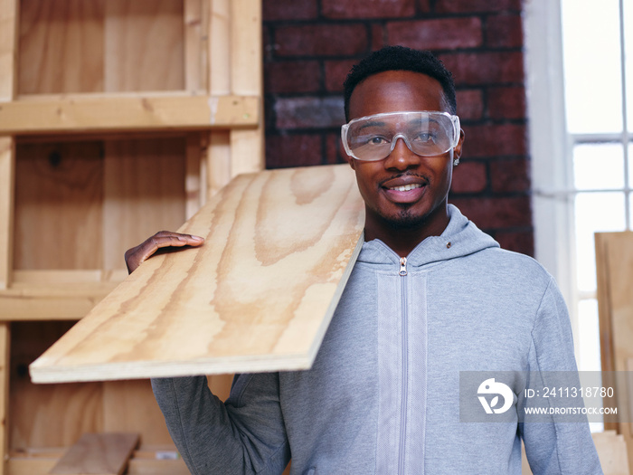 Portrait of carpenter holding plank