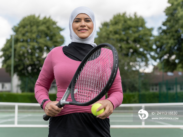 UK,Sutton,Portrait of smiling woman in headscarf at tennis court