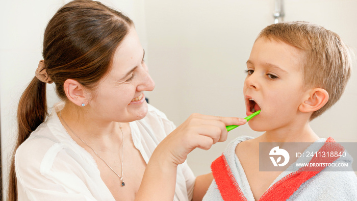 Young smiling mother brushing and cleaning teeth of her little son with tothbrush. Concept of child dental hygiene and healthcare at home. Caring parents and kids at home.