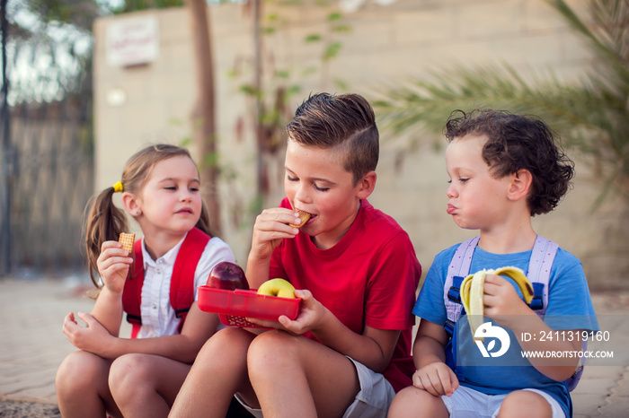 Pupils having lunch time outdoor. Children, education and nutrition concept