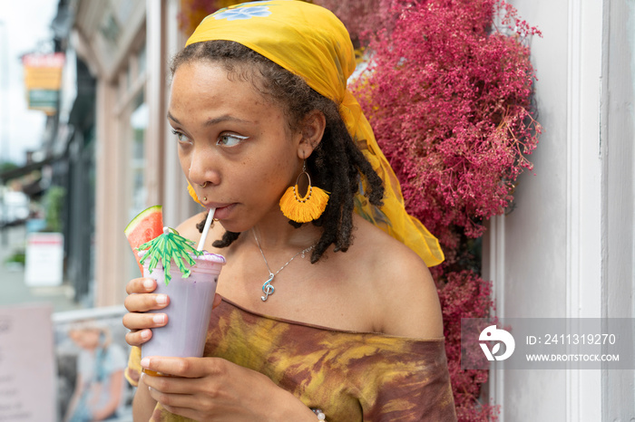 Portrait of young woman drinking smoothie in city