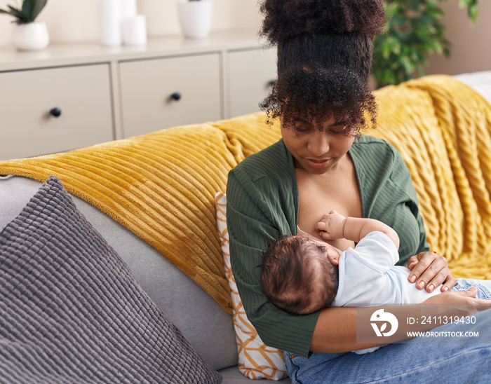 Mother and son sitting on sofa breastfeeding at home