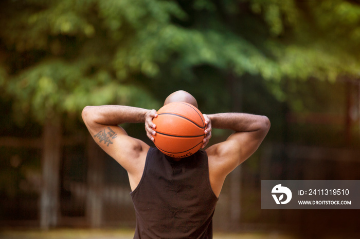 Rear view of man throwing basket ball in court