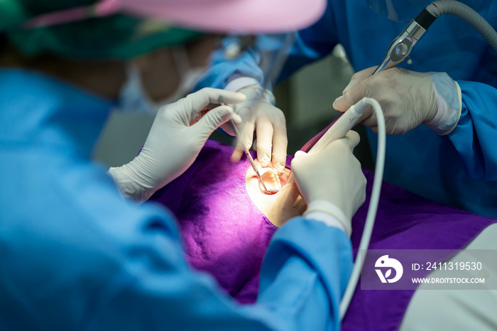 Dentist with an assistant in protective gloves are examining her teeth with a help of a dental bur with a mirror and an air polisher. Caries healing. Examination of the dentist.