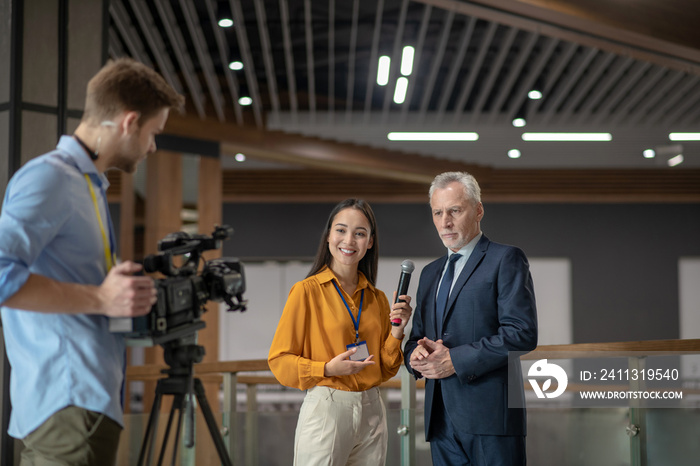 Reporters with videocamera having interview with famous businessman