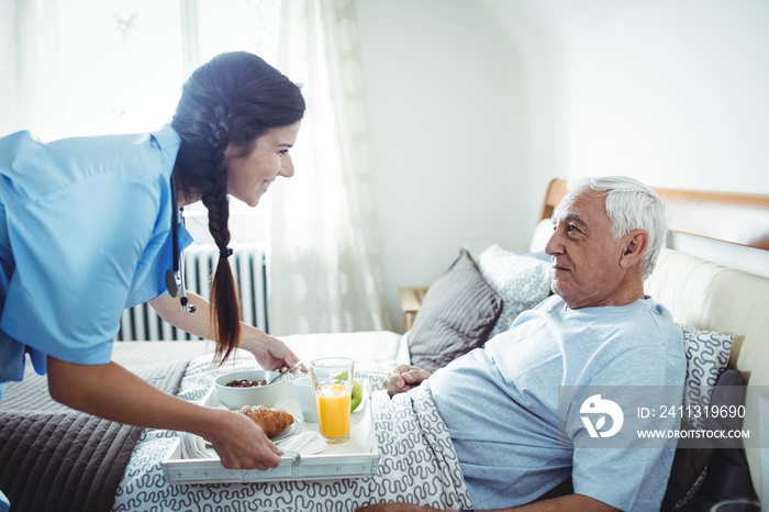 Nurse serving breakfast to senior man