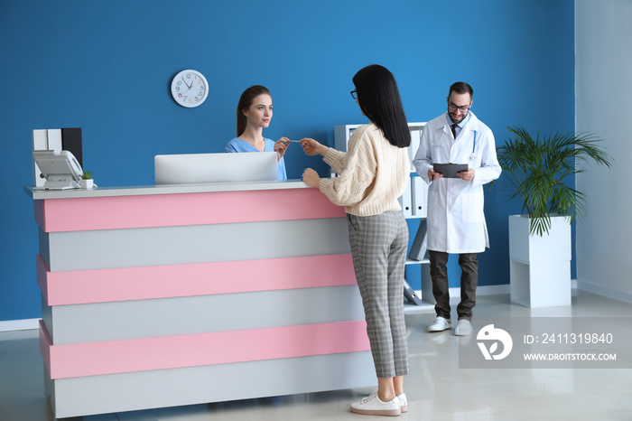 Female receptionist receiving payment for medical service from patient in clinic