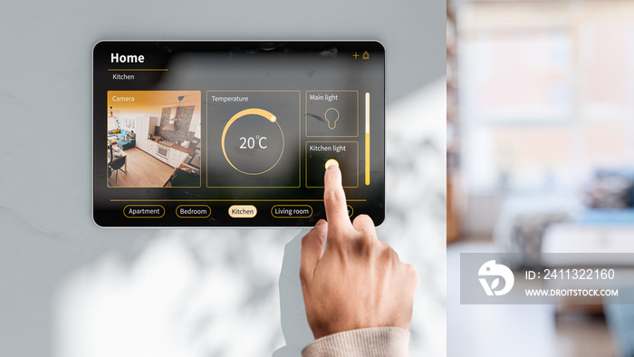 The man changes the settings on the tablet to control a smart home - an example of an interface with a camera view, controlling the light and room temperature