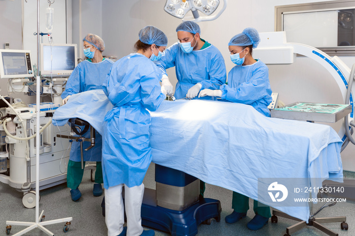 Group of medical team urgently doing surgical operation and helping patient in theater at hospital. Medical team performing surgical operation in a bright modern operating room