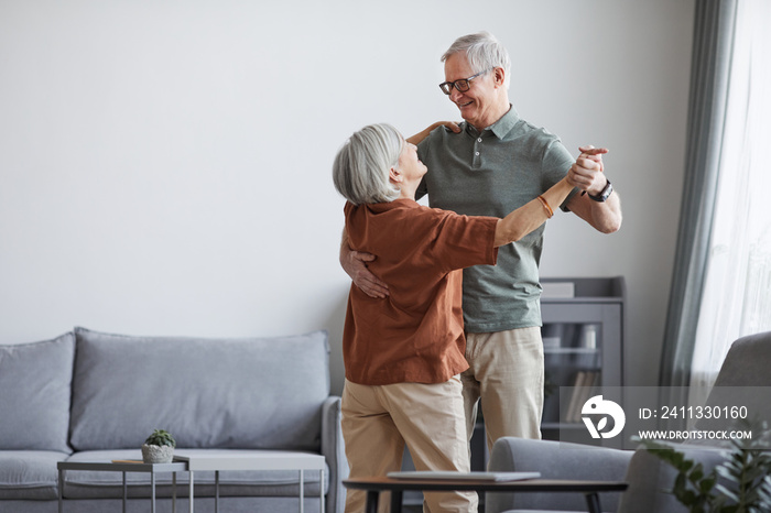 Minimal portrait of loving senior couple dancing at home together, copy space