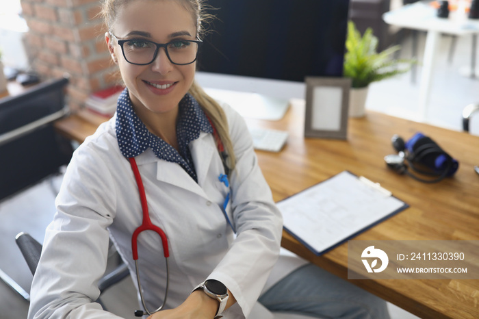 Cheerful doctor in uniform, stethoscope tool on neck, modern clinic office