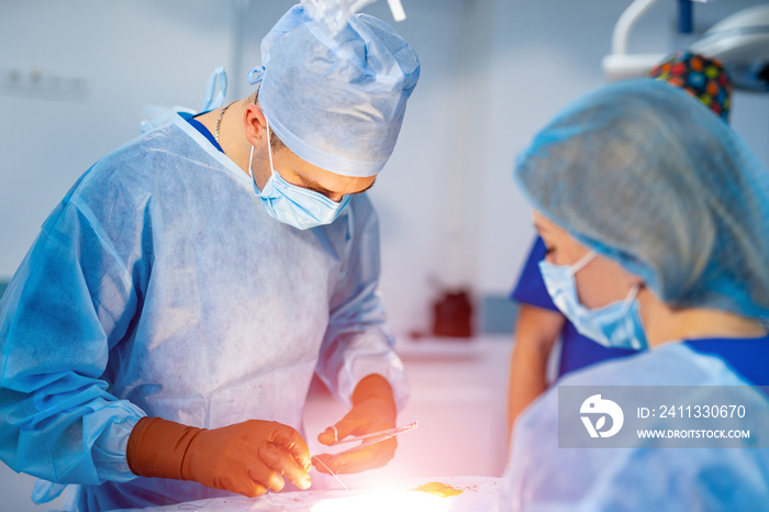 Work of surgeons in operating room with modern equipment. Group of doctors perform an operation to a patient.