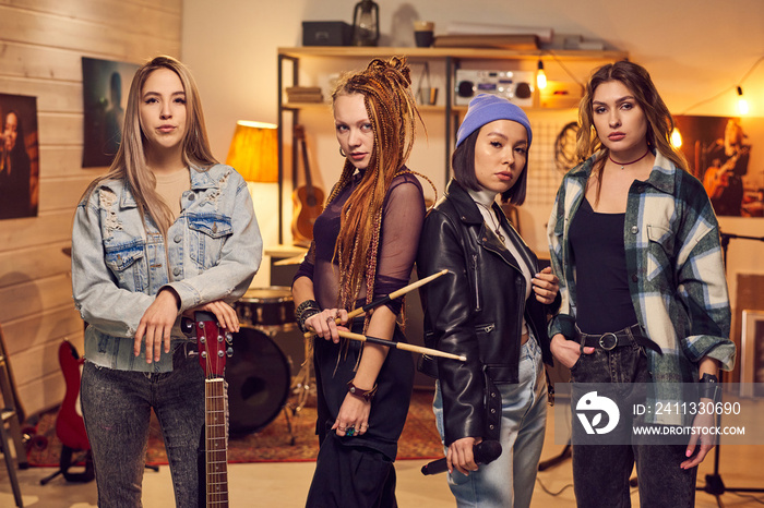 Girl band consisting of four females standing in row in studio