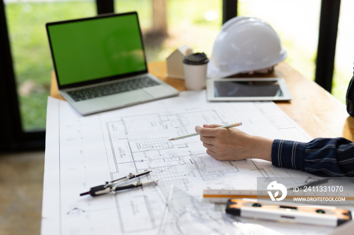 Top view, Architect or engineer hands working on blueprint plans  with a pencil and laptopa ruler, calculator,  and engineering tools.    Woman architect or engineer working on blueprint in office.