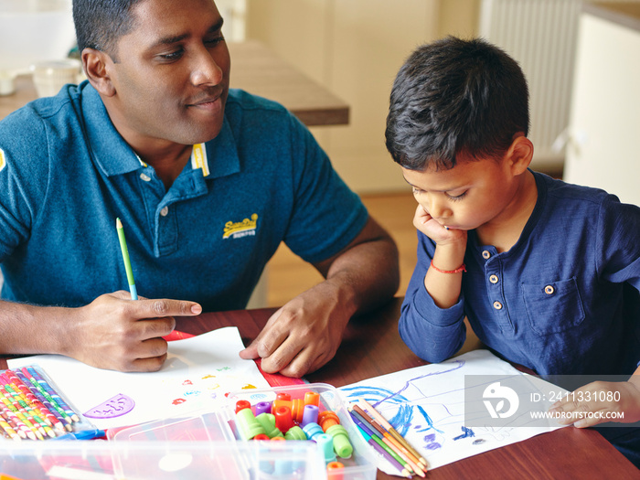 Father and son drawing at kitchen table