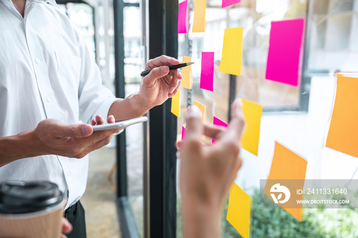 Creative team using post it notes in glass wall to writing strategy